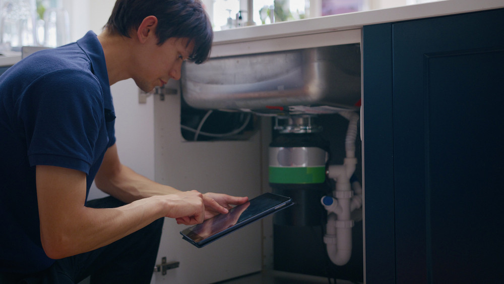 Plumber performing a plumbing camera inspection at kitchen drain